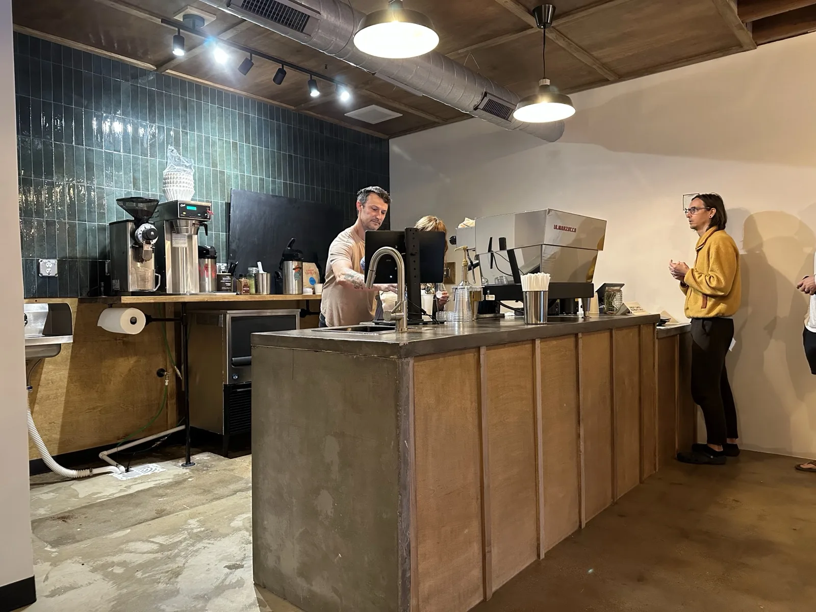 Richie at the concrete coffee bar pulling espresso with a customer at the counter